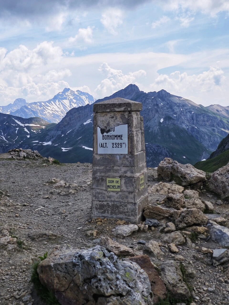 La borne du col du Bonhomme à 2 329 m, avec les crêtes enneigées dans les nuages